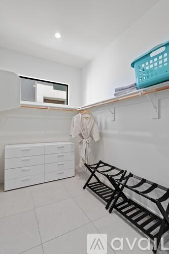 A laundry room with a clothes drying rack and a basket on top of the shelf.