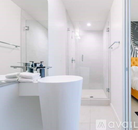 A white bathroom with a round sink and a glass shower stall.