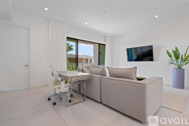 A modern living room with a grey sofa, a white chair, and a television mounted on the wall.