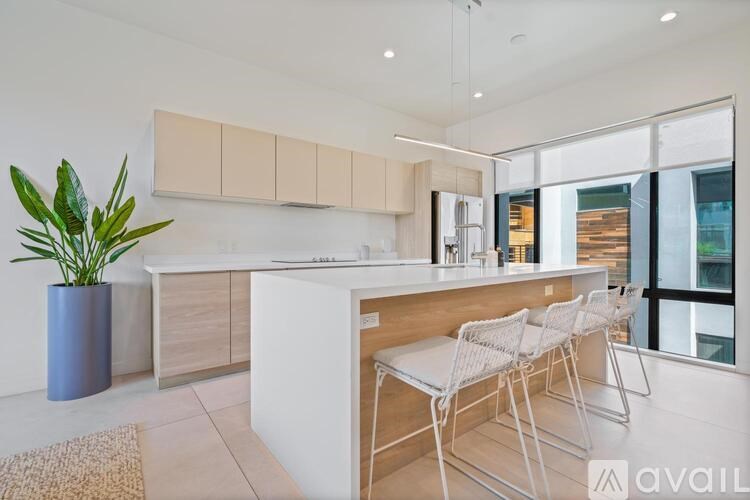 A modern kitchen with white chairs and a wooden counter.