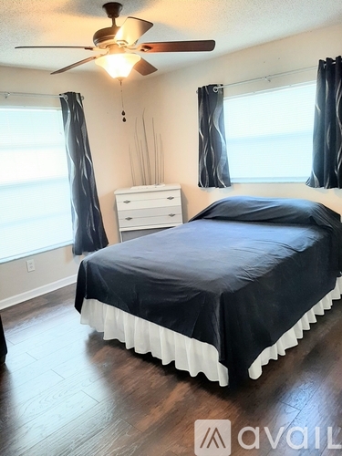 A bedroom with a bed, dresser, and ceiling fan.