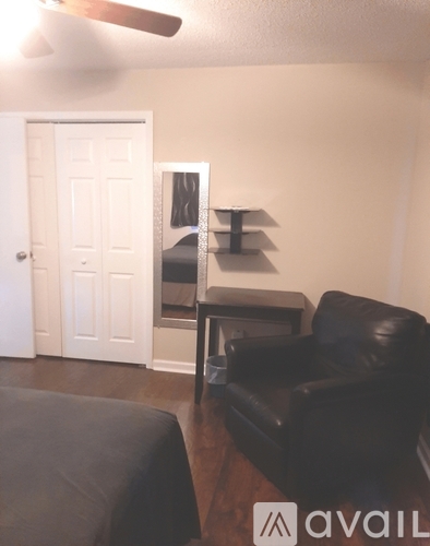 A black leather couch in a living room with a white door in the background.