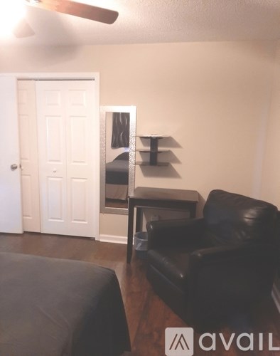A black leather couch in a living room with a white door in the background.