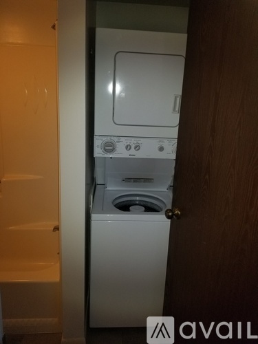A white dishwasher is in a narrow space between a door and a wall.