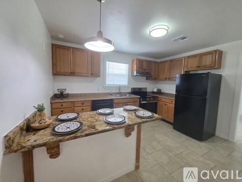 A kitchen with a black refrigerator and wooden cabinets.