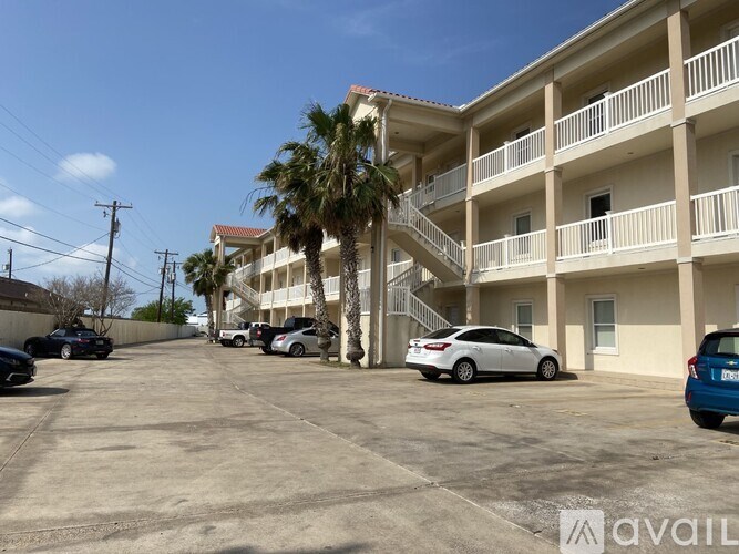 A parking lot with cars and a building with balconies in the background.