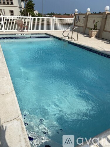 A swimming pool with a white fence and a diving board.