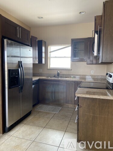 A kitchen with a refrigerator, microwave, and oven.