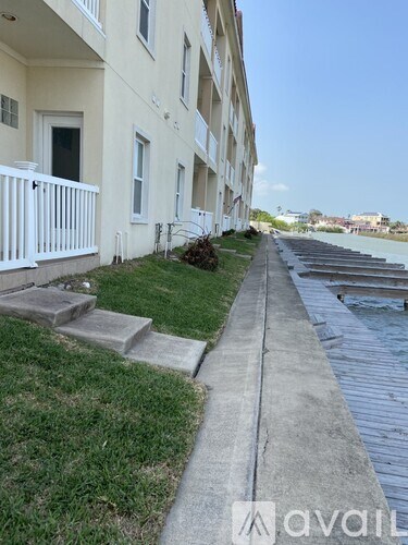 A white building with a balcony overlooking a concrete walkway.