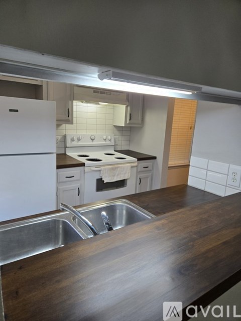 A kitchen with a white fridge, stove, and wooden countertop.