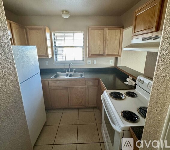 A kitchen with white appliances and wooden cabinets.