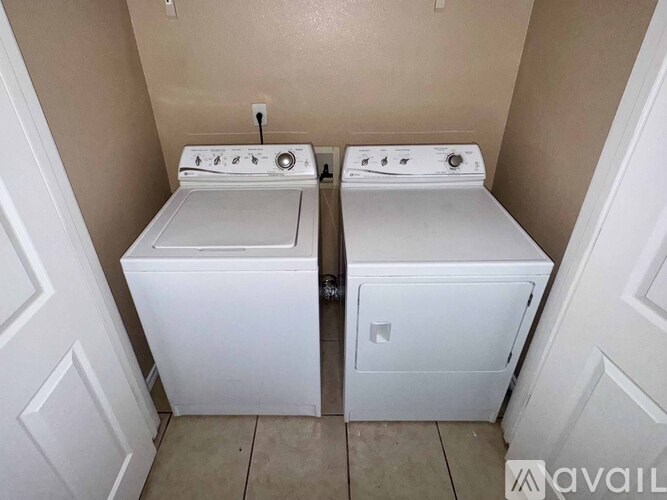 Two white front load washing machines in a small laundry room.