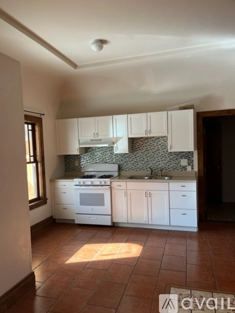 A kitchen with white cabinets and a tiled floor.