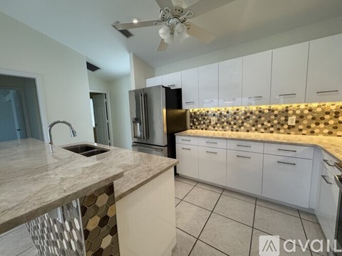 A kitchen with white cabinets and a marble countertop.