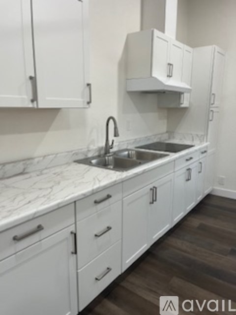 A kitchen with white cabinets and a marble countertop.
