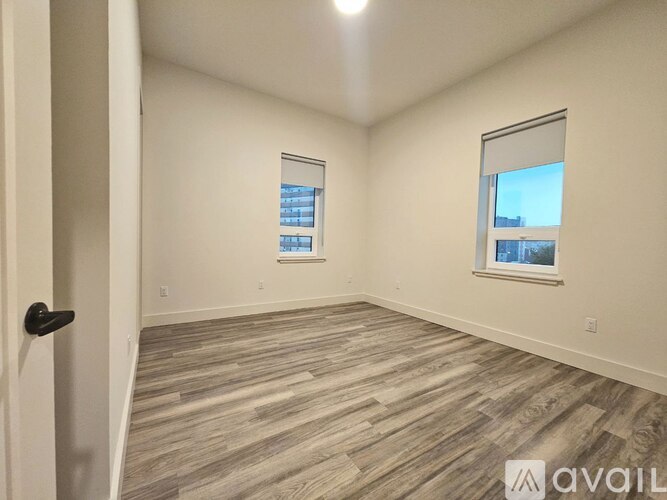 A room with wooden flooring and a window showing a cityscape.