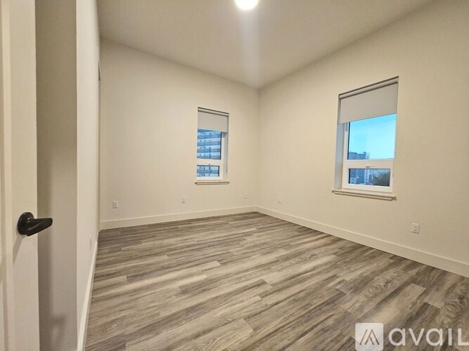 A room with wooden flooring and a window showing a cityscape.