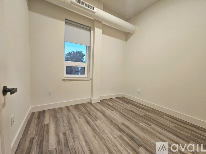 A room with a window and wooden flooring is available for rent.