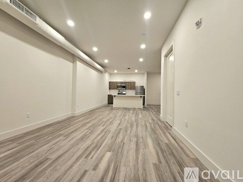 A long, empty hallway with wood flooring and white walls.