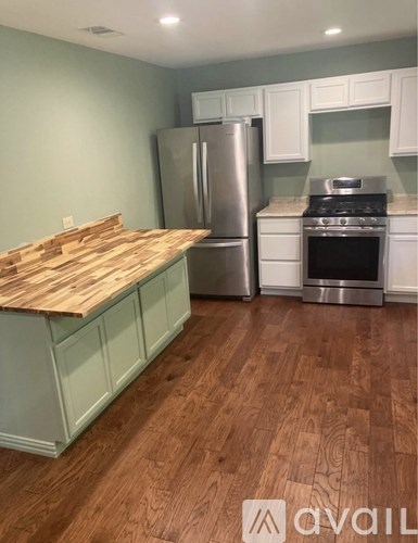 A kitchen with a wooden counter top and stainless steel appliances.