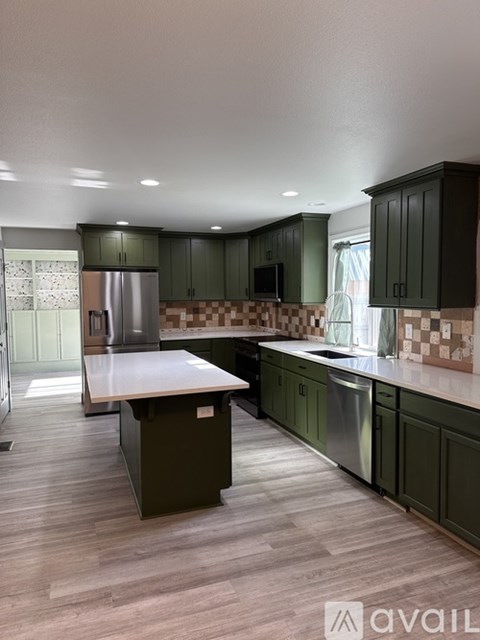 A kitchen with green cabinets and a checkered backsplash.