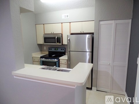 A kitchen with a white counter and stainless steel appliances.