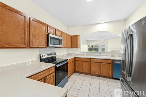 A kitchen with wooden cabinets and a stainless steel refrigerator.