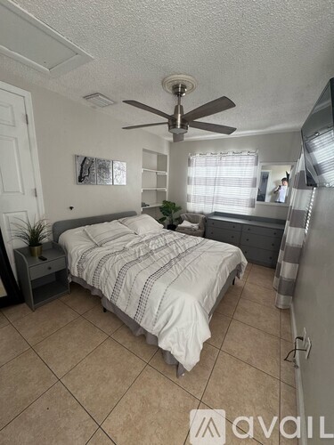 A bedroom with a bed, dresser, and ceiling fan.