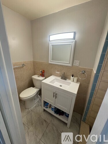 A bathroom with a toilet, sink, and mirror.