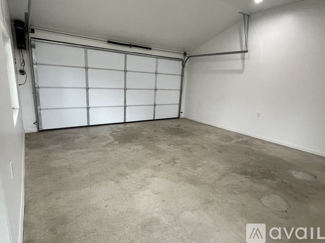 A spacious garage with a white door and a concrete floor.