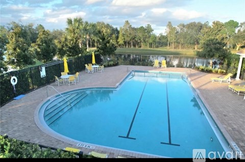 A large outdoor swimming pool surrounded by trees and lounge chairs.
