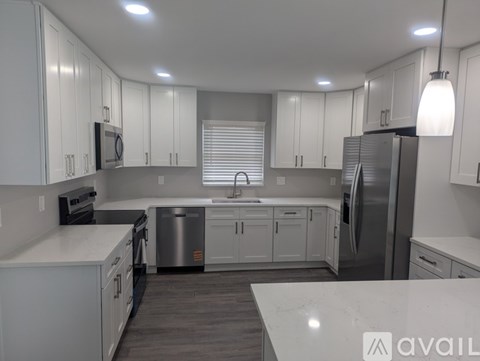 A modern kitchen with white cabinets and stainless steel appliances.