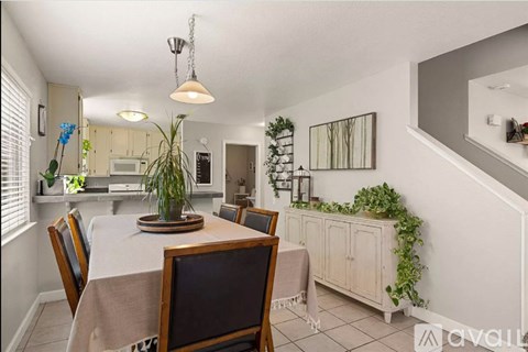 A dining room with a table set for four and a kitchen in the background.
