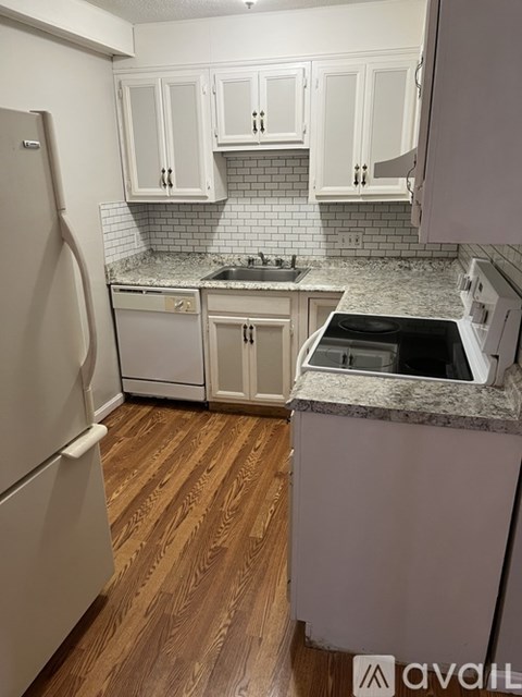 A kitchen with a white fridge and wooden floors.