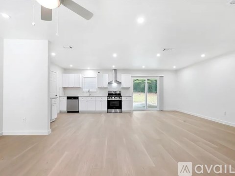 A spacious kitchen with white cabinets and a wooden floor.