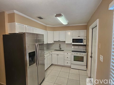A kitchen with white cabinets and a black refrigerator.