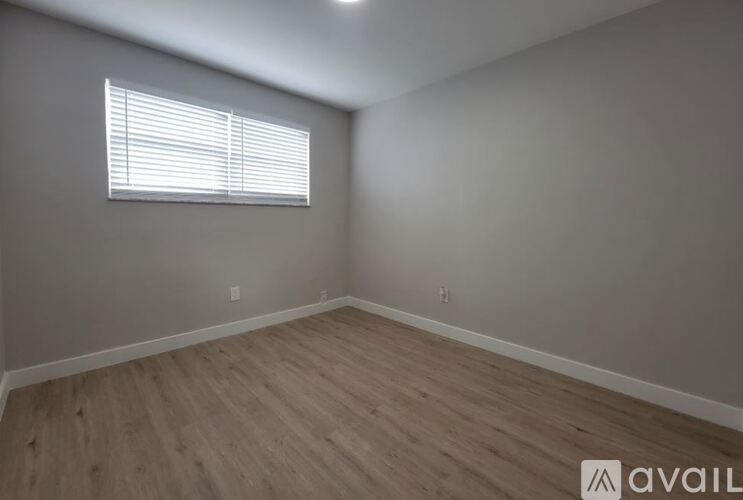 A room with wooden flooring and a window with blinds.
