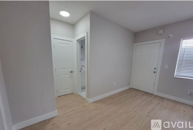 A room with two doors and a window with blinds.