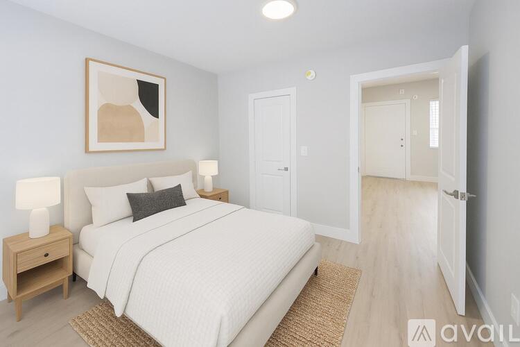 A bedroom with a large bed, a nightstand with a lamp, and a painting on the wall.