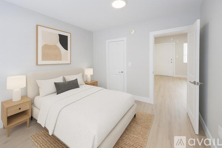 A bedroom with a large bed, a nightstand with a lamp, and a painting on the wall.