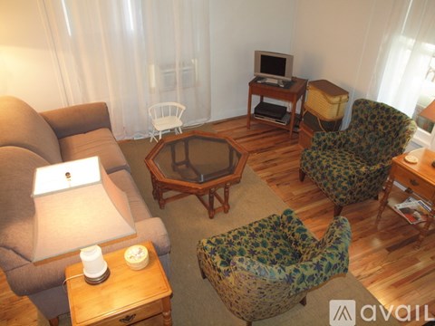 A living room with a brown couch, a green patterned chair, a wooden coffee table, and a television on a stand.