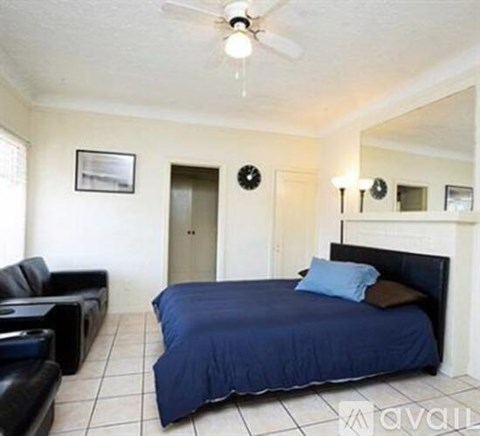 A bedroom with a bed, couch, and mirror.