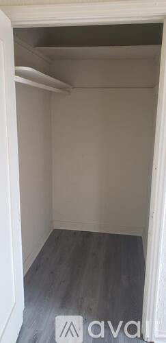 A white door is open to a room with grey flooring.