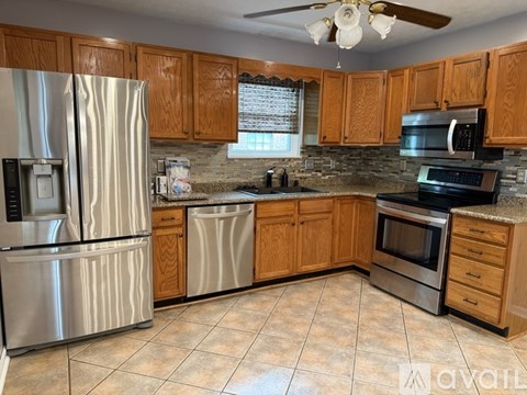 A kitchen with wooden cabinets and a stainless steel refrigerator.