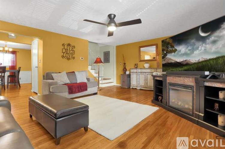 A living room with a fireplace and a painting of a mountain landscape on the wall.