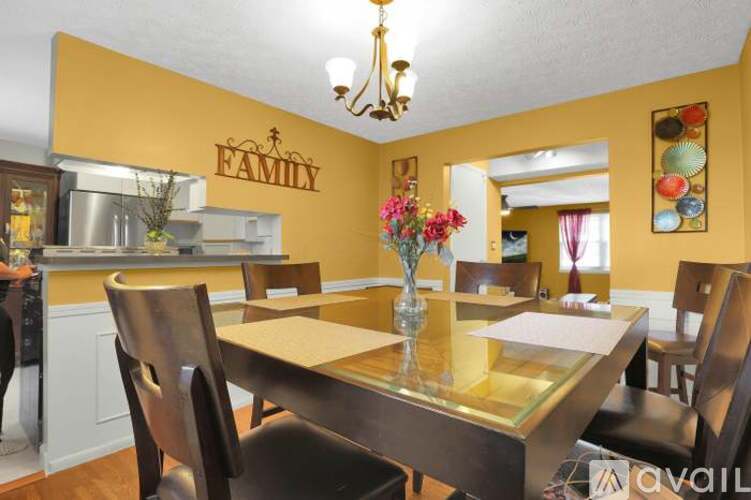 A dining room with a table set for four and a chandelier hanging from the ceiling.