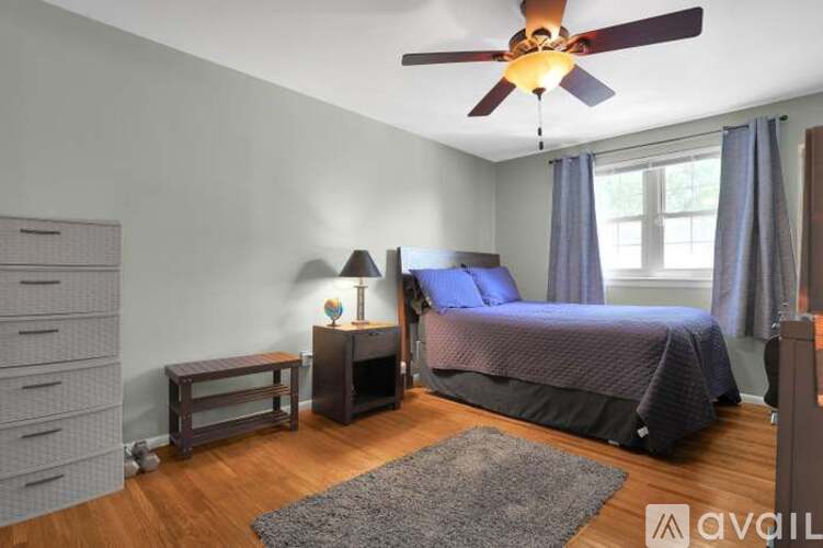 A bedroom with a bed, nightstand, and a ceiling fan.