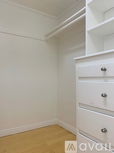 A white drawer is in the corner of a room.