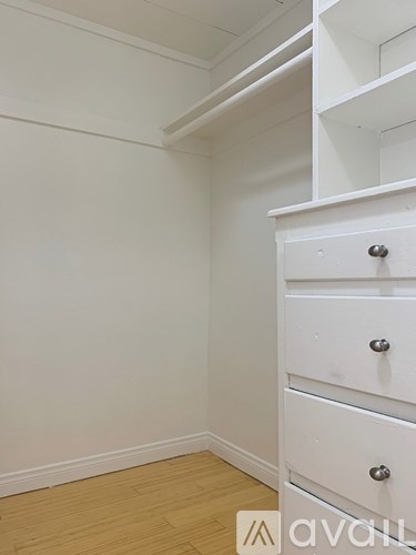 A white drawer is in the corner of a room.