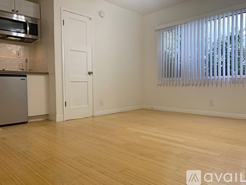 A kitchen with a wooden floor and a window with blinds.